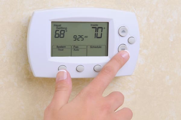 person pushing down arrow on thermostat